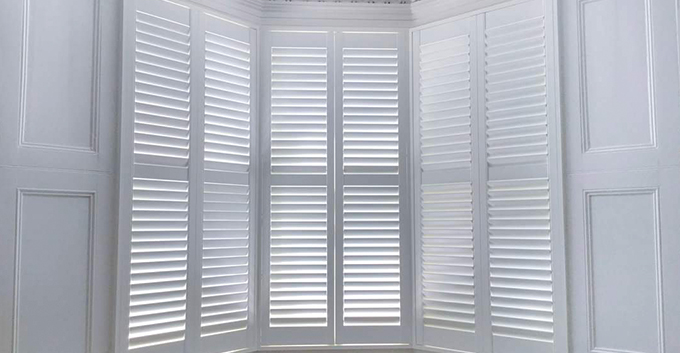 a white bay shutter covering the height of a window in a white bay area of a house