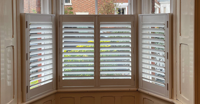cafe style shutters installed on half a tall window